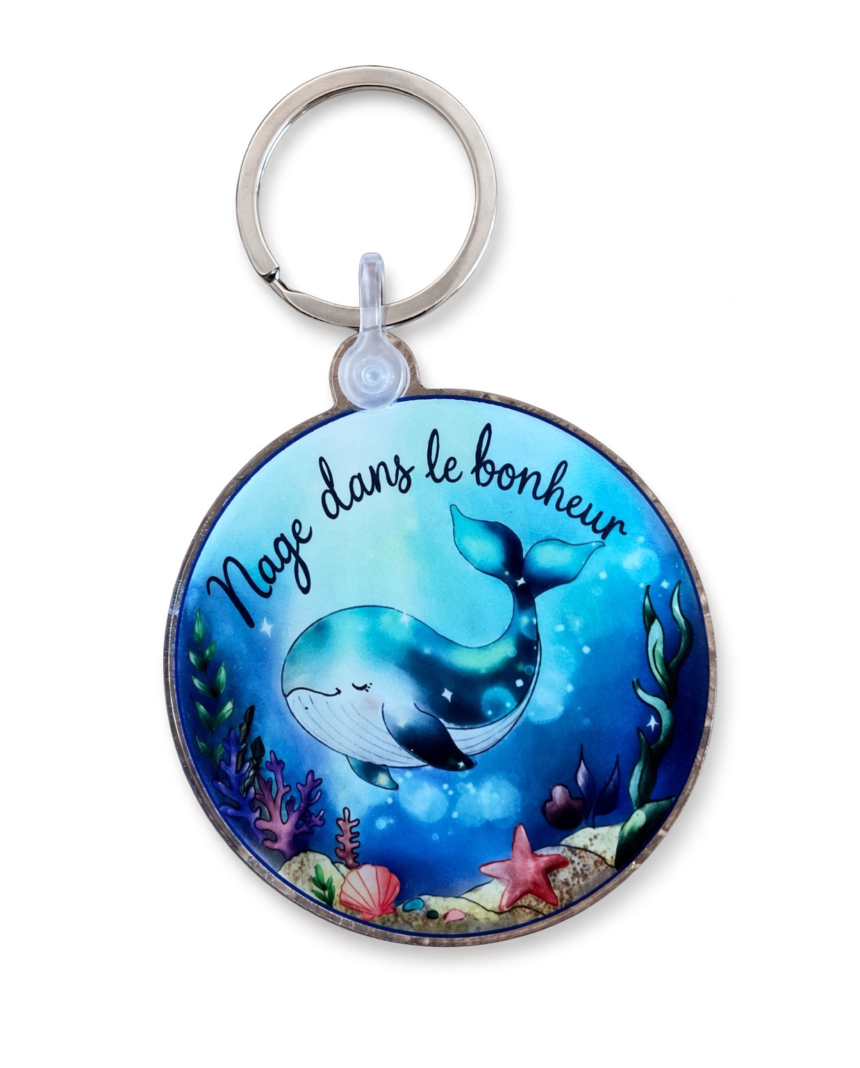 Porte-clés rond en acrylique avec une baleine bleue et le message Nage dans le bonheur, sur fond blanc